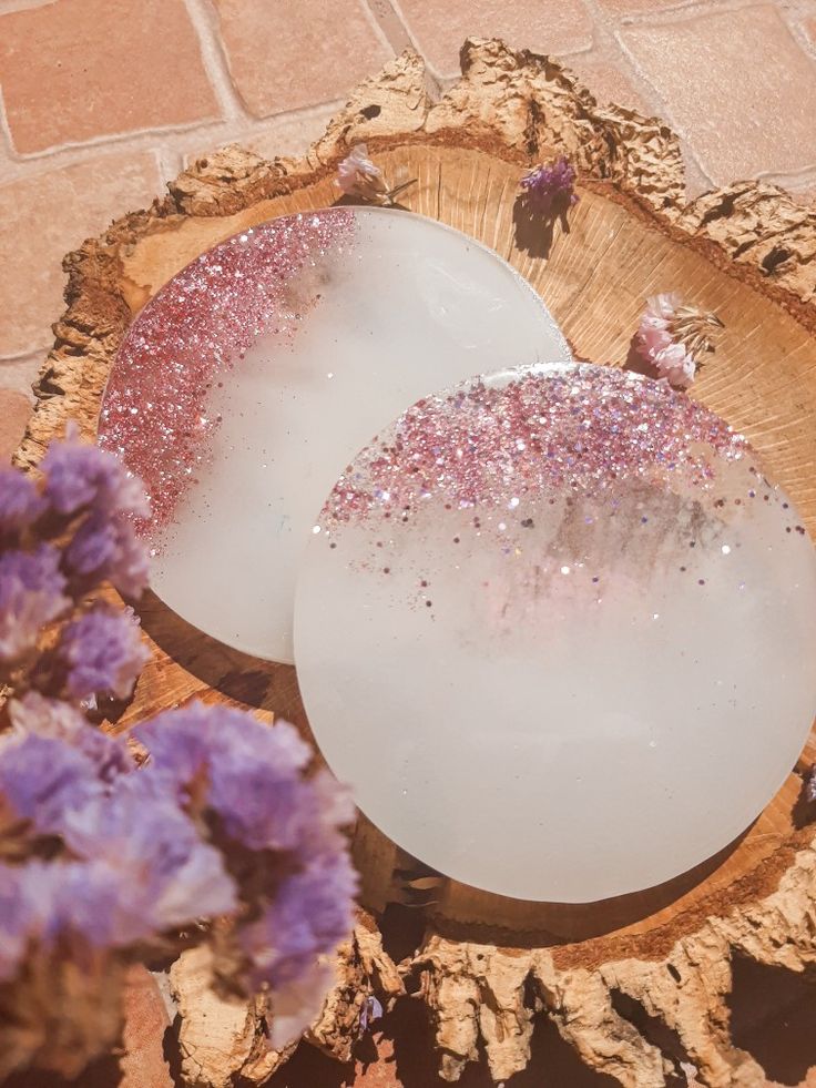 two soap dishes sitting on top of a wooden tray next to purple and white flowers