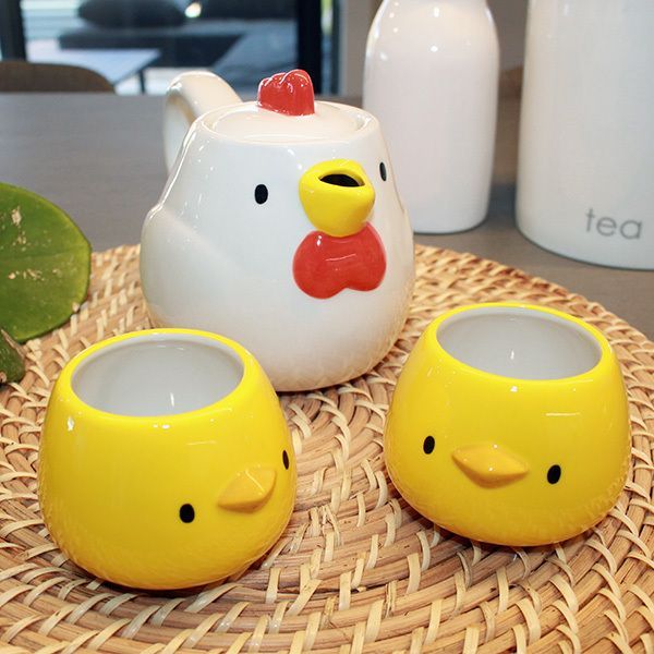 three yellow chickens sitting on top of a wicker table next to two white vases