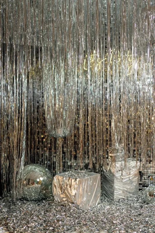 some glass balls and tinsel hanging from the ceiling in front of a mirror wall