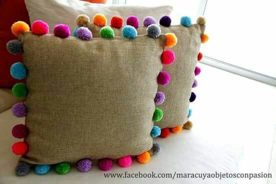 two pillows with colorful pom - poms on them sitting next to each other