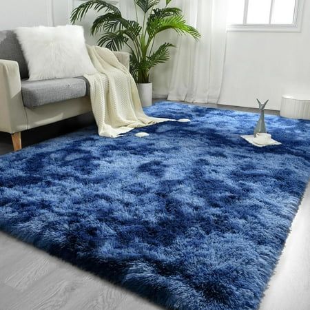 a living room with a couch, chair and rug in blue tones on the floor