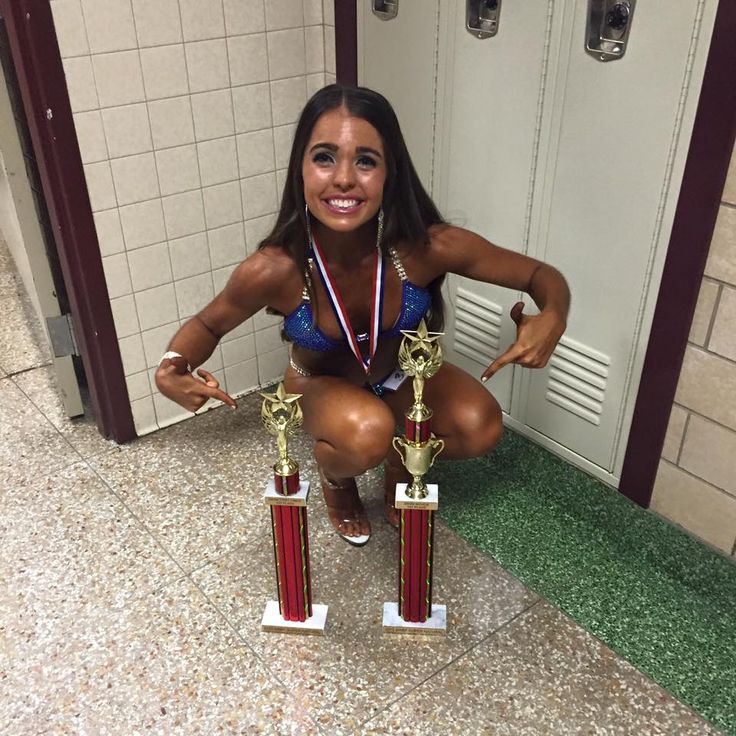 a woman kneeling down with two trophies in front of her