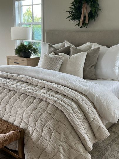 a large bed sitting in a bedroom next to a window with wreath on the wall