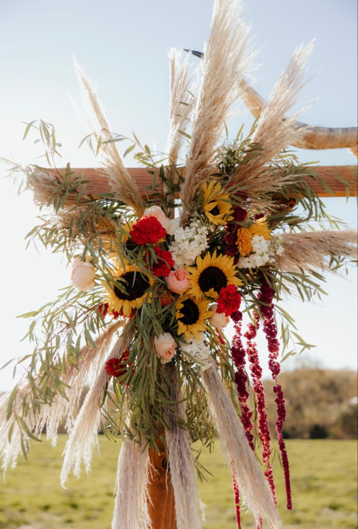 an arrangement of flowers and feathers on a wooden pole