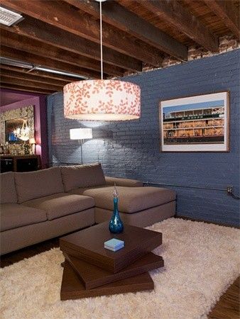 a living room with a couch, coffee table and lamp on the wall next to it