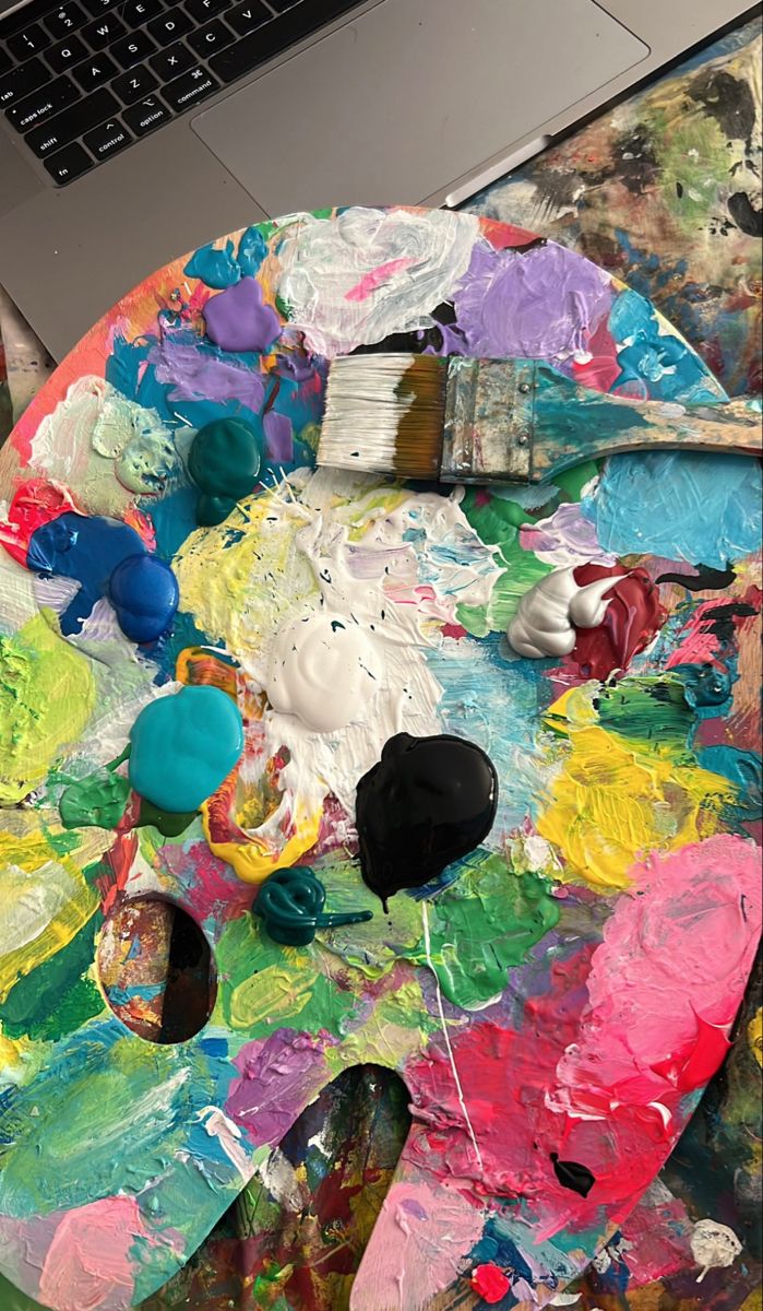 a paint palette sitting on top of a table next to a laptop computer