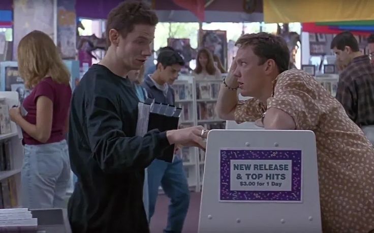 two men are talking to each other in a book store