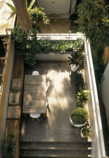 an overhead view of a small patio with table and chairs, potted plants on either side