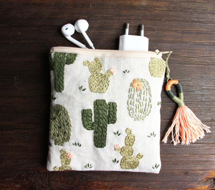 a cactus print pouch with earbuds and headphones in it on a wooden surface