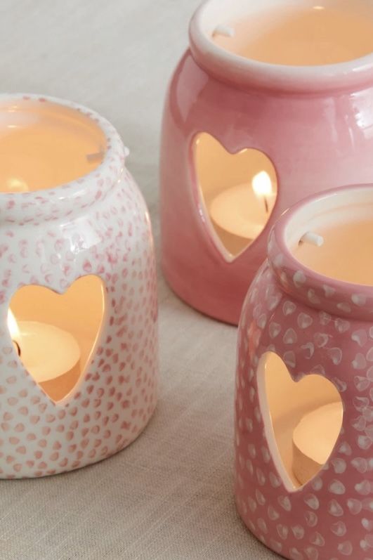 three pink candles with hearts cut out of them sitting next to each other on a table