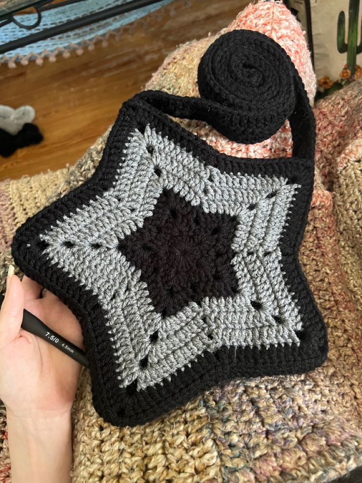 a person is holding a crocheted bag with a black and white square on it