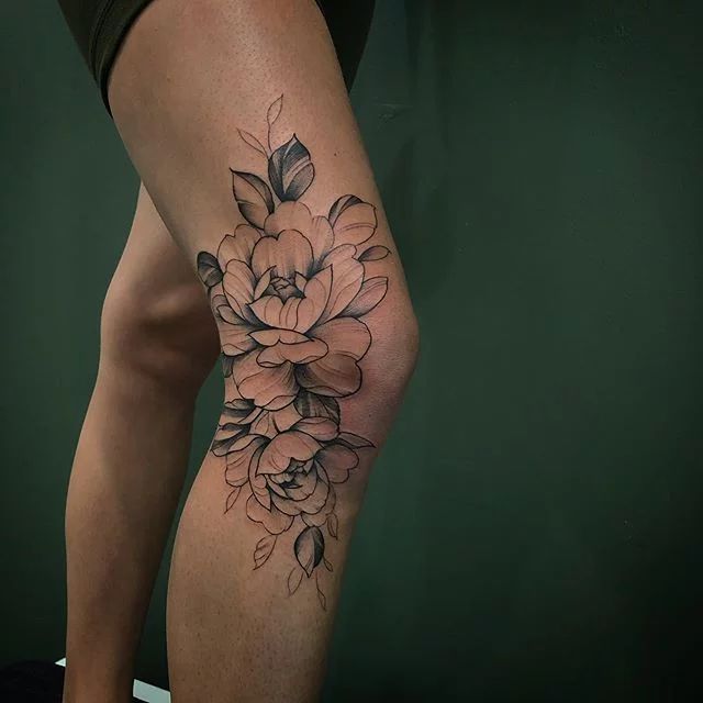 a woman's leg with a flower tattoo on the side of her thigh,