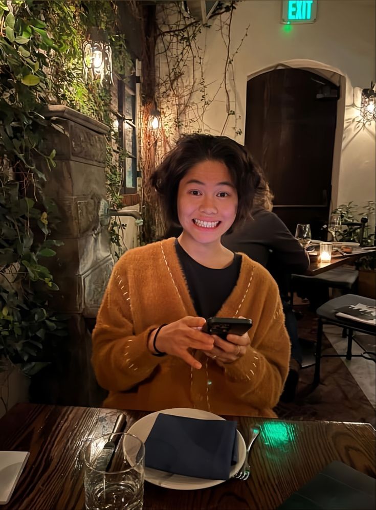 a woman sitting at a table with a cell phone