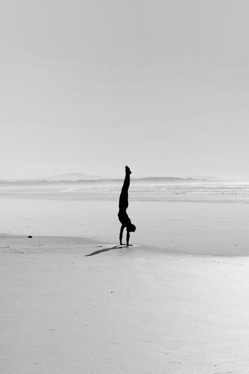 a person doing a handstand on the beach