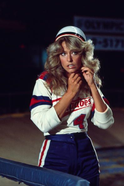 a woman in sailor's outfit standing next to a bench with her hands on her chest