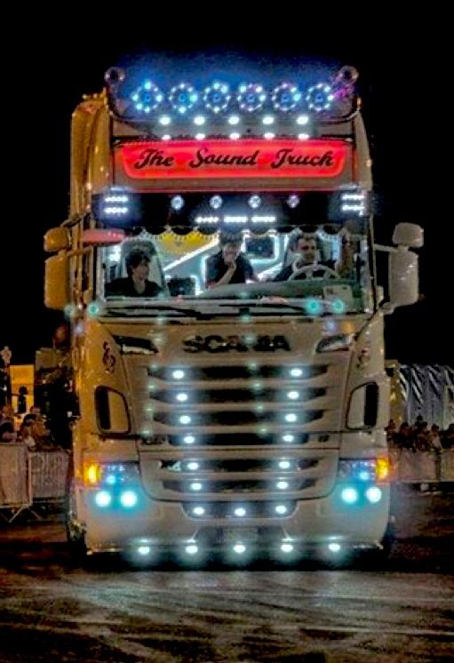 a large truck driving down a street at night with lights on it's sides