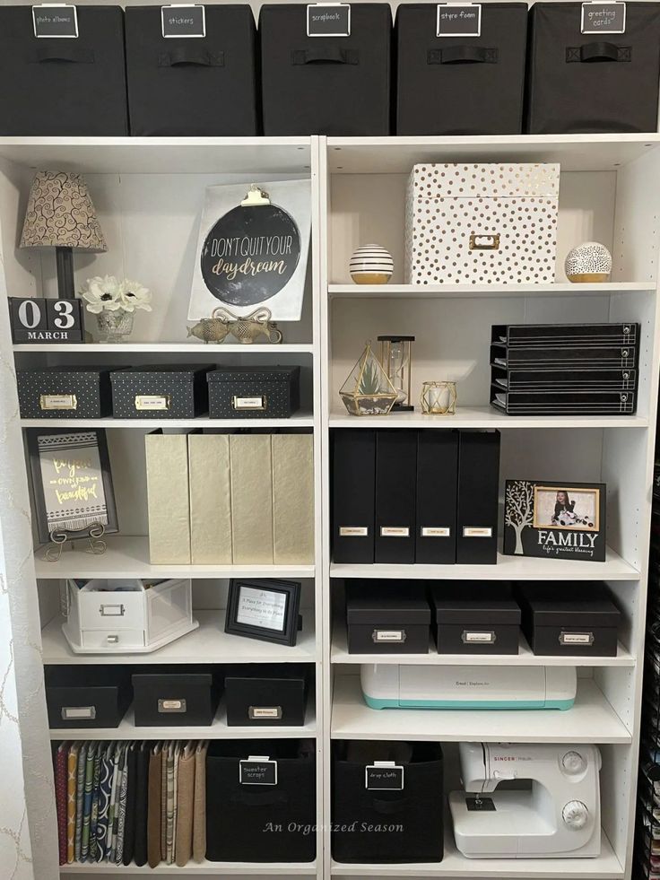 a white bookcase filled with lots of black and white boxes on top of it