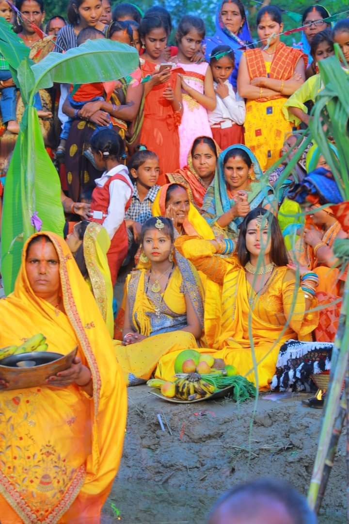 a group of women dressed in yellow sitting on the ground