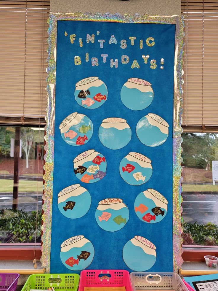 a bulletin board with fish in it and some plastic bins on the table next to it