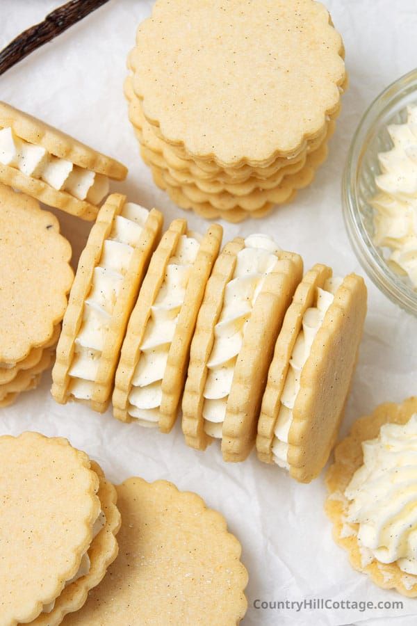 cookies with white frosting on top are arranged next to a bowl of whipped cream