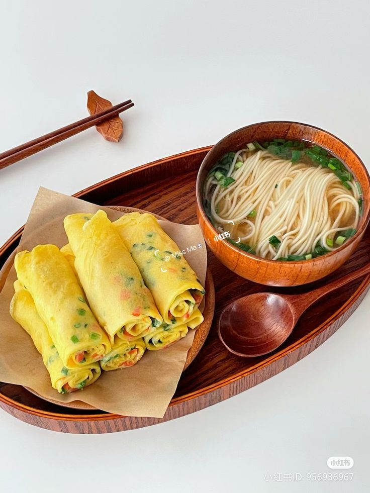 a wooden tray with some food and chopsticks on it