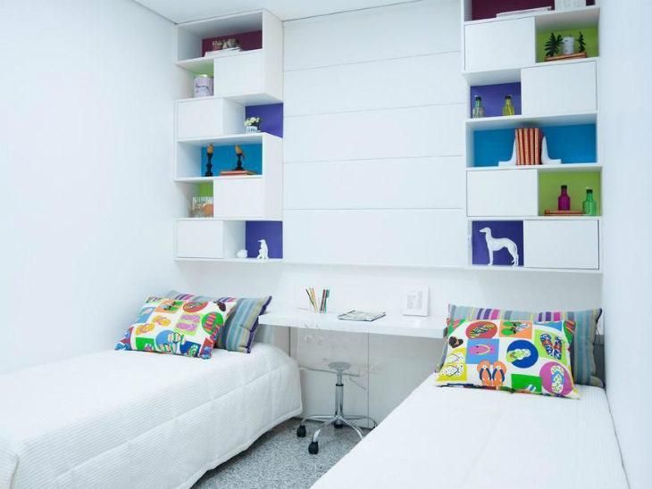 two beds in a small room with white walls and shelves on the wall behind them