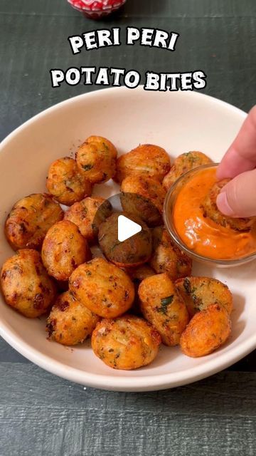 a person dipping something into a bowl with some sort of sauce on it and the words peri peri potato bites