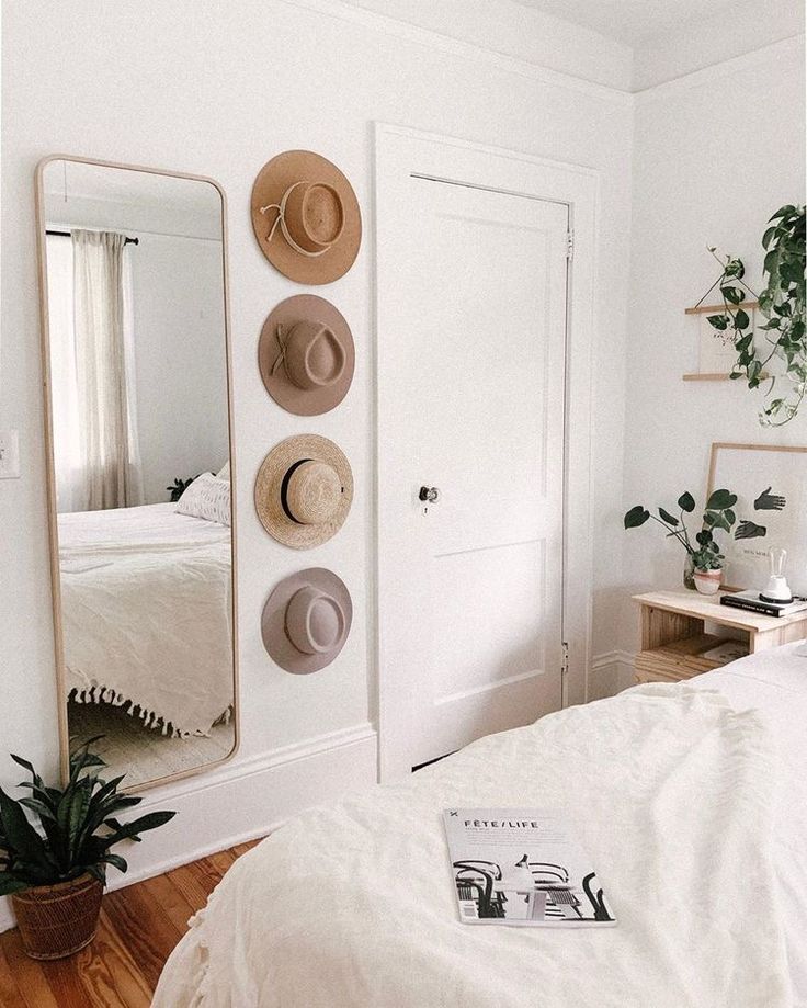 a bedroom with a bed, mirror and potted plant on the floor in front of it