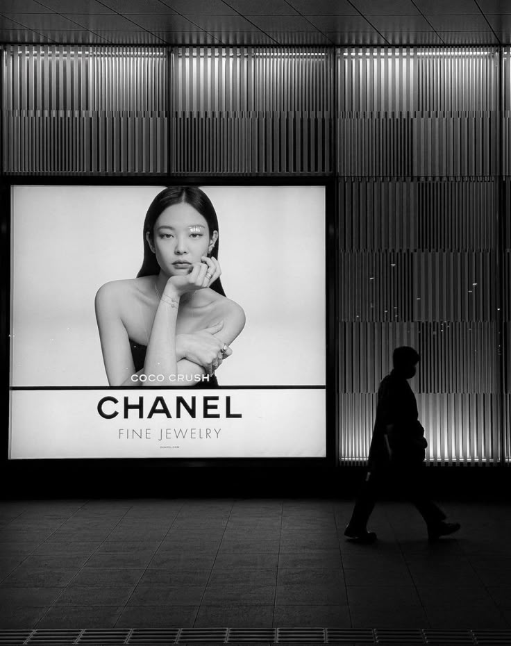 a woman walking past a chanel advertisement