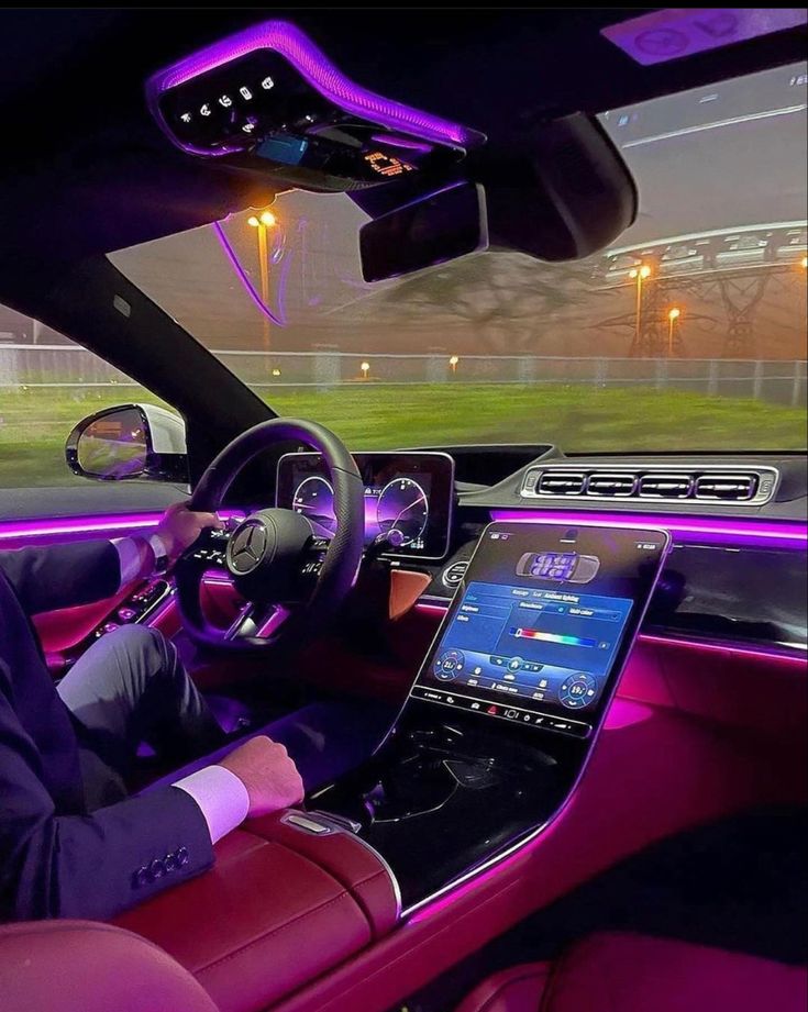 a man in a suit driving a car with purple lights on the dash and dashboard