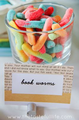 a glass bowl filled with lots of colorful candies next to a sign that says book worms