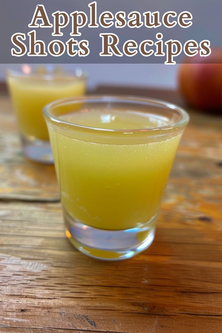 two shot glasses filled with apple juice on top of a wooden table