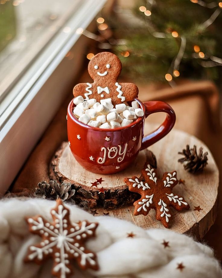 a cup filled with marshmallows sitting on top of a wooden slice next to a window