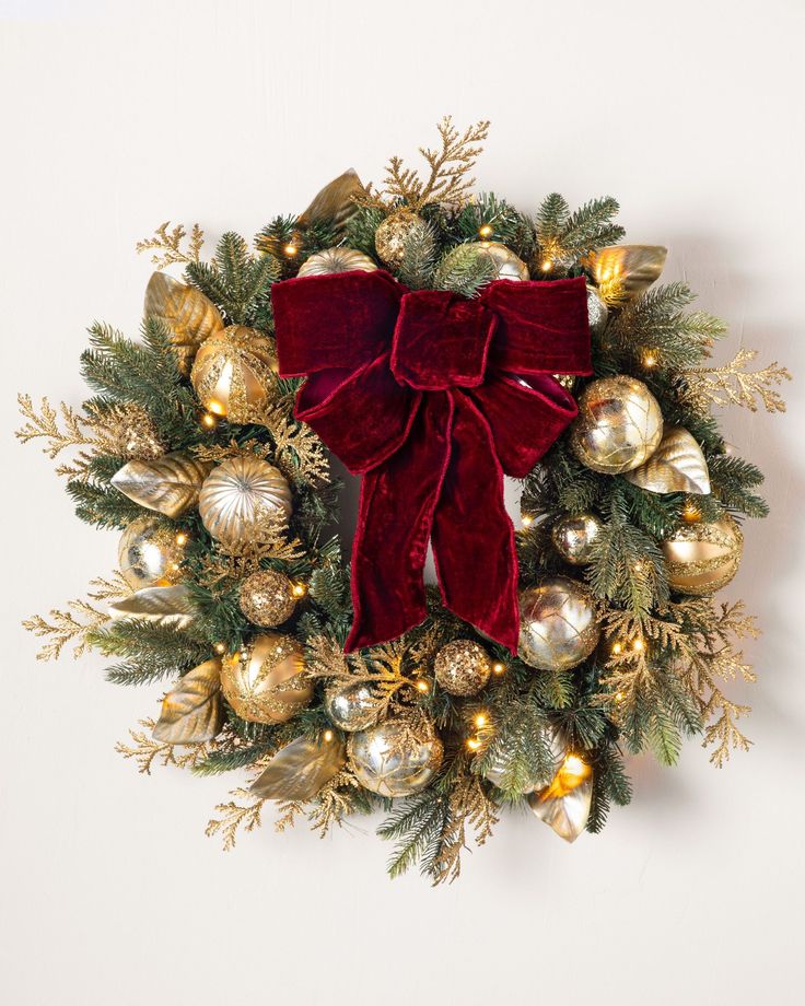 a christmas wreath with red velvet bow and gold ornaments