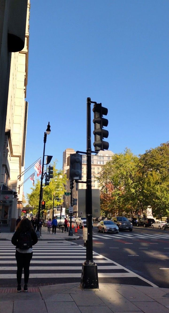 a woman is standing on the sidewalk near a traffic light