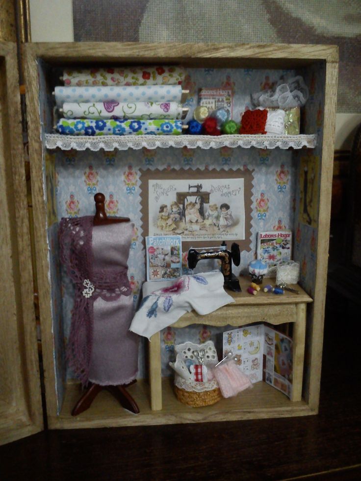 a dollhouse is shown with sewing supplies on the shelf and in front of it