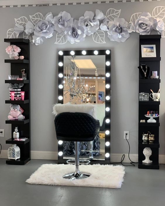 a salon chair sitting in front of a large mirror with lights on the wall behind it