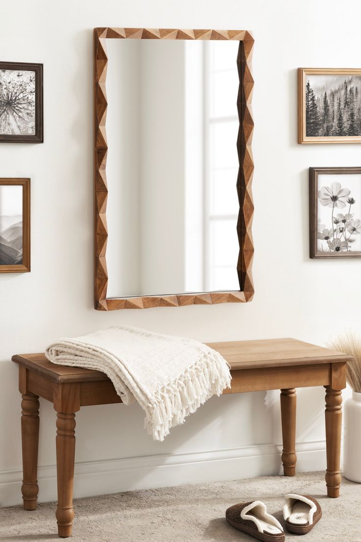 a wooden bench sitting under a mirror next to a pair of slippers on the floor