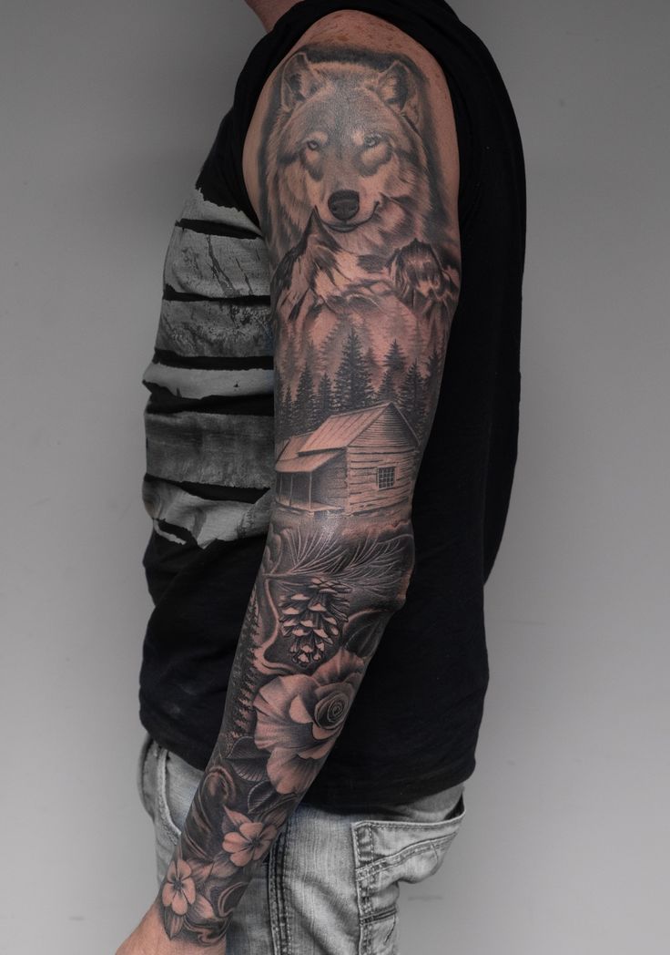 a man's arm with a wolf and flowers tattoo on his left arm,