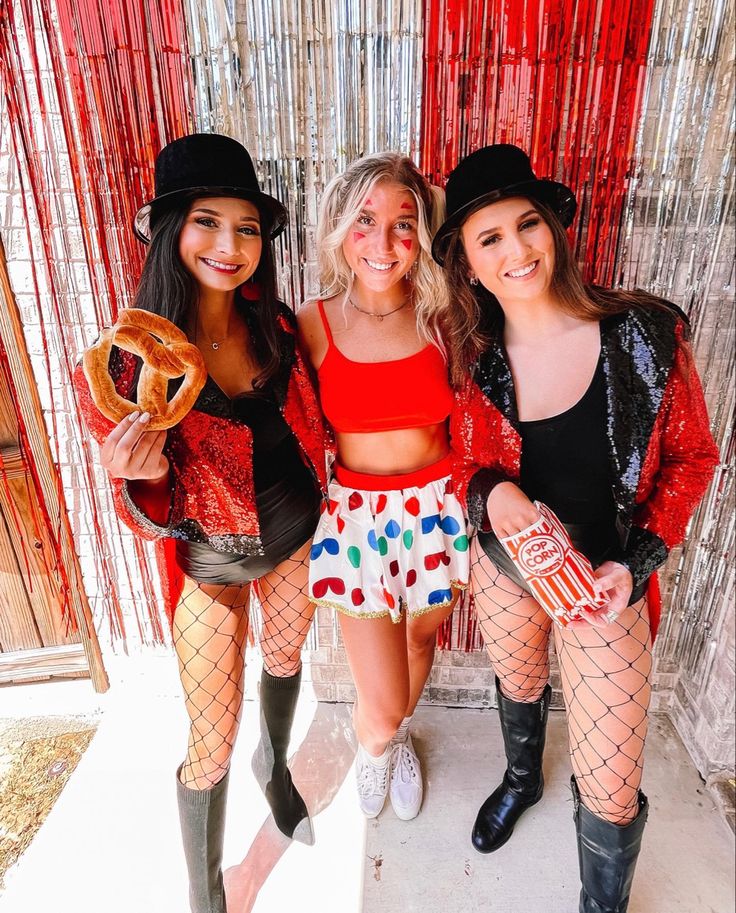 three young women dressed in costumes posing for the camera with one holding a bagel