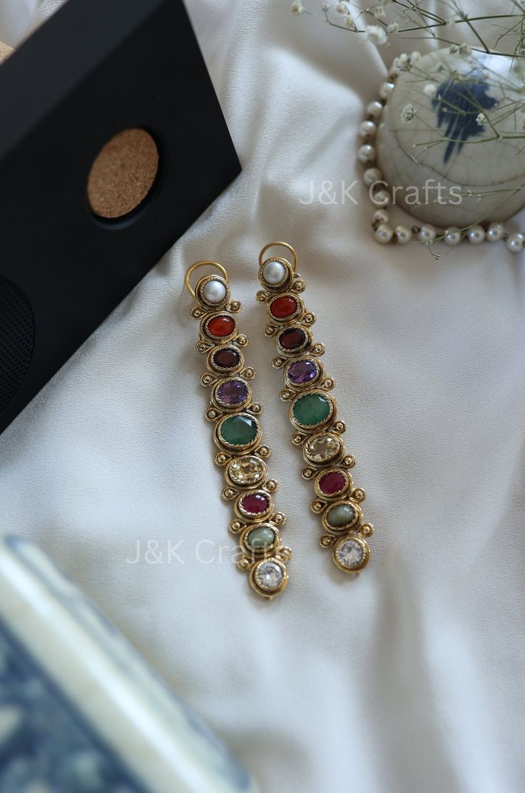 These Multicolored earrings are adorned with vibrant navrattan stones, making them perfect statement pieces. Their contemporary design adds a touch of modern elegance to any outfit. Stand out with these encrusted earrings that are sure to turn heads. Closure - Push Back Weight - 51gm (Pair) Luxury Hallmarked Fusion Earrings, Handmade Multicolor Temple Jewelry Earrings, Fusion Style Multicolor Earrings For Festivals, Fusion Style Multicolor Danglers For Gift, Fusion Style Multicolor Danglers As Gift, Multicolor Fusion Danglers For Gift, Multicolor Fusion Earrings For Festivals, Multicolor Fusion Style Earrings For Festivals, Elegant Multicolor Danglers For Festive Occasions