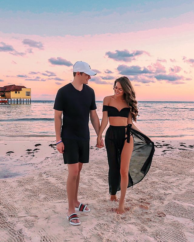 a man and woman walking on the beach holding hands