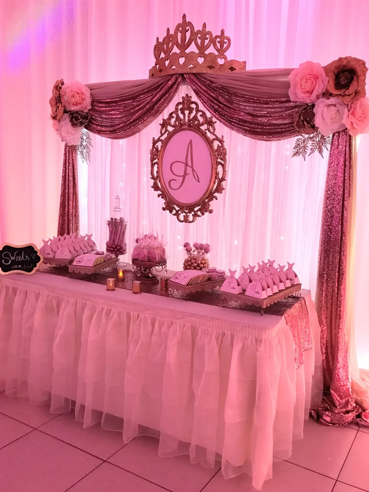 a table topped with lots of desserts under a pink lite up stage curtain