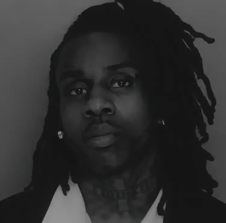 a black and white photo of a man with dreadlocks looking at the camera