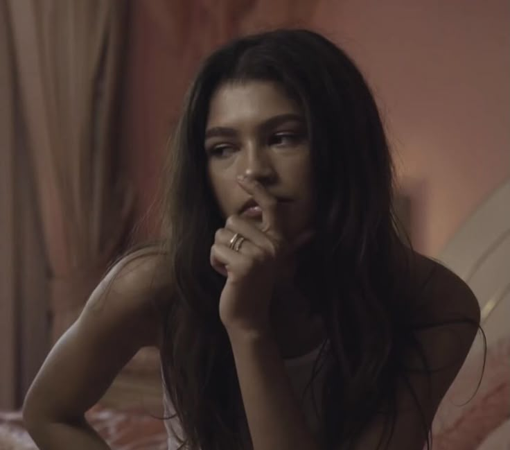 a woman with her hand on her mouth looking at the camera while sitting in bed