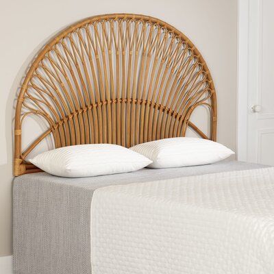 a wicker headboard with two pillows on top of it in a white bedroom