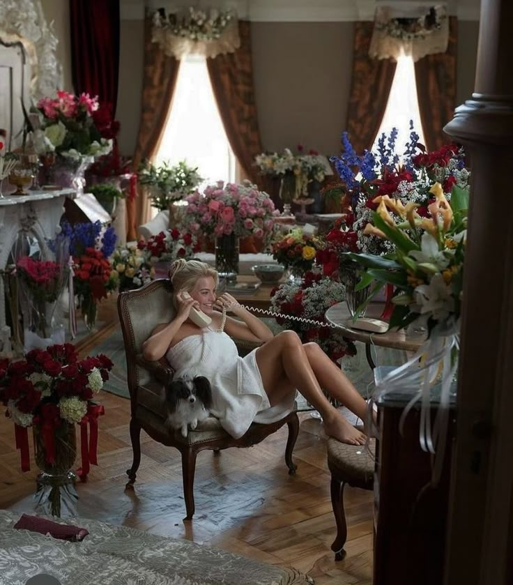 a woman sitting in a chair talking on a cell phone next to flowers and candles