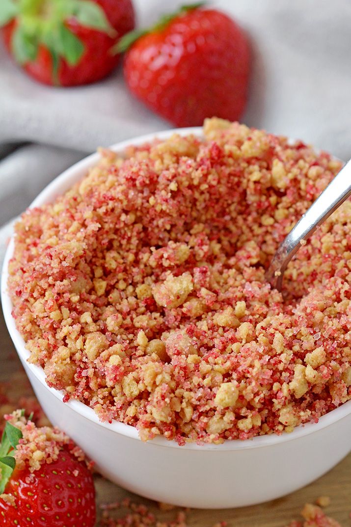 a bowl filled with crumbs next to two strawberries