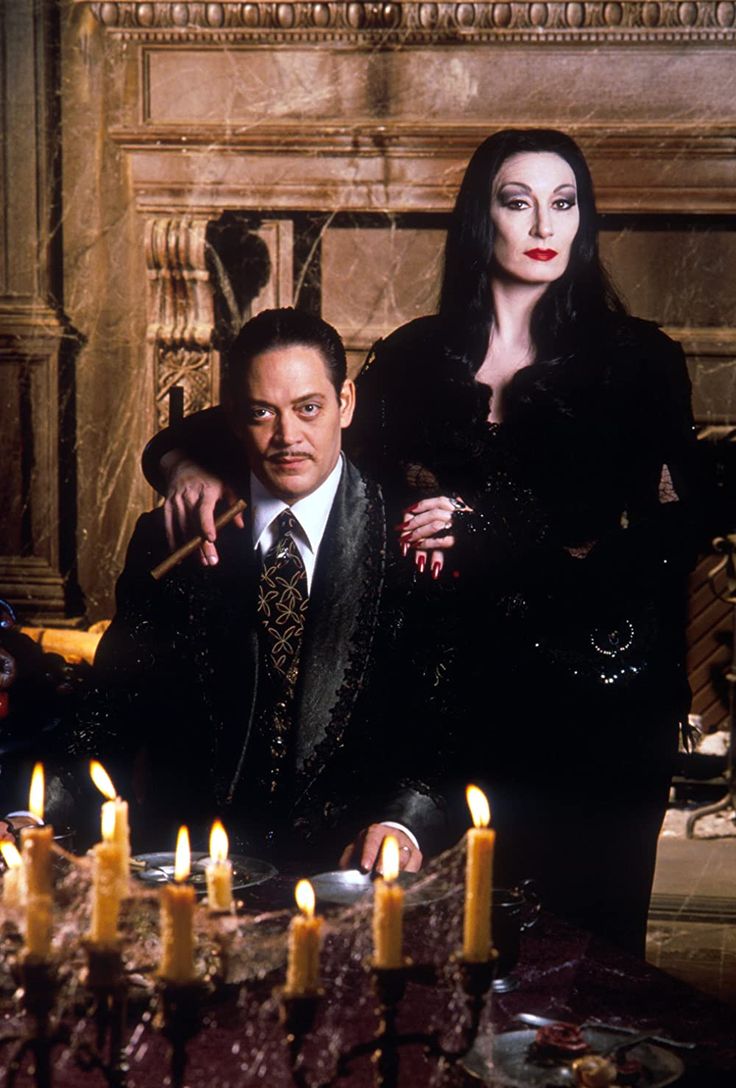 a man and woman sitting at a table with candles in front of them on the set of maleficent