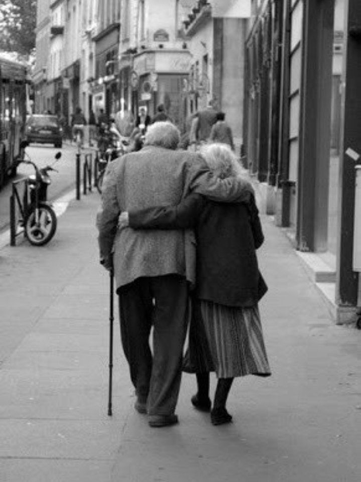 an old couple walking down the street with their back to each other and holding hands